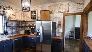 Une cuisine équipée d’un réfrigérateur en acier inoxydable, de meubles de rangement en bois et d’un espace dédié à la préparation du café.