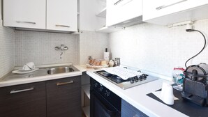 Une cuisine moderne avec des meubles blancs, un évier en acier inoxydable et une cuisinière à gaz.