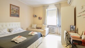 Une chambre à coucher avec un lit, un canapé, un bureau et une fenêtre avec des rideaux.