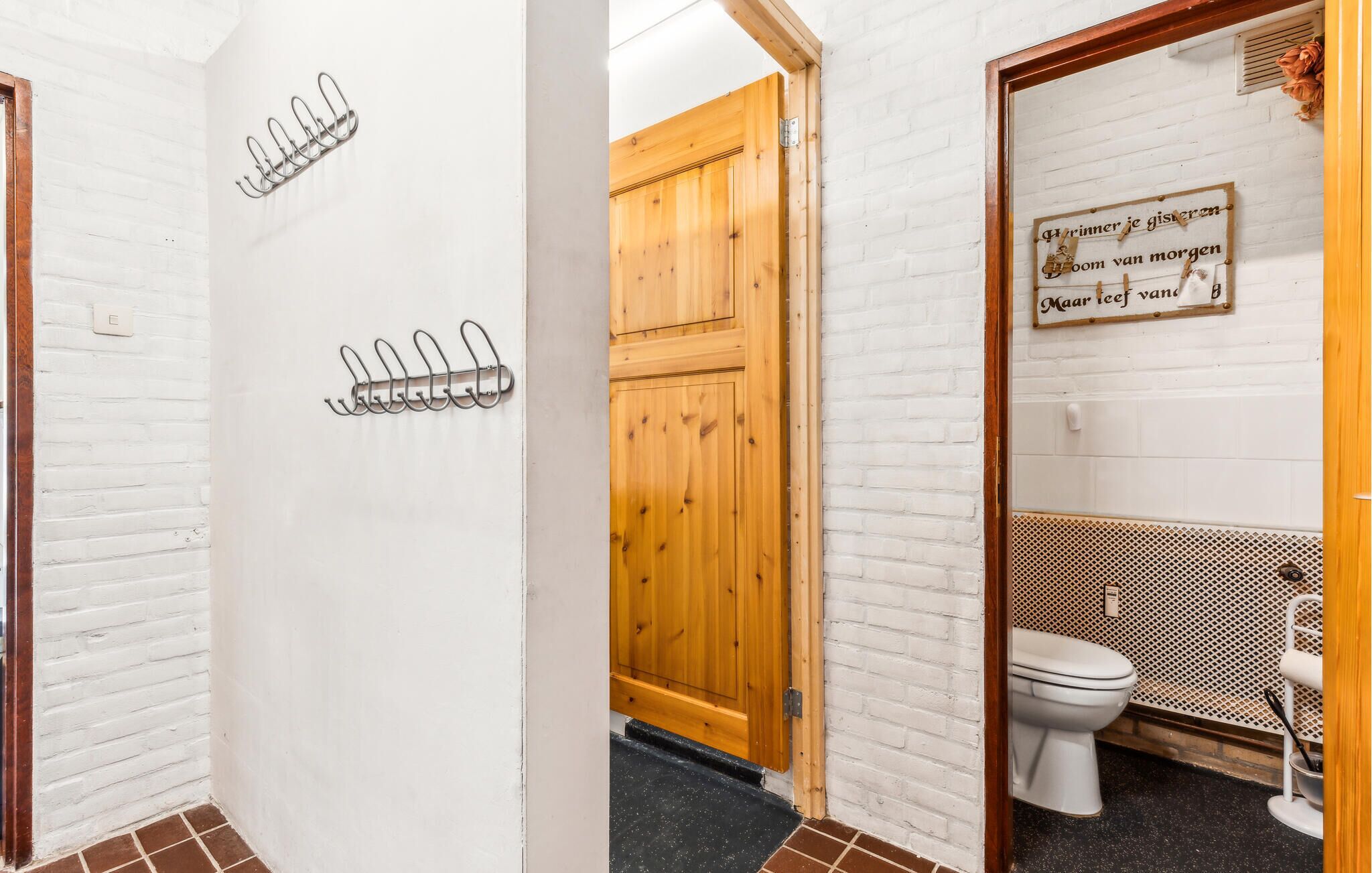 Ein Badezimmer mit Holztür, Toilette und Duschbereich.