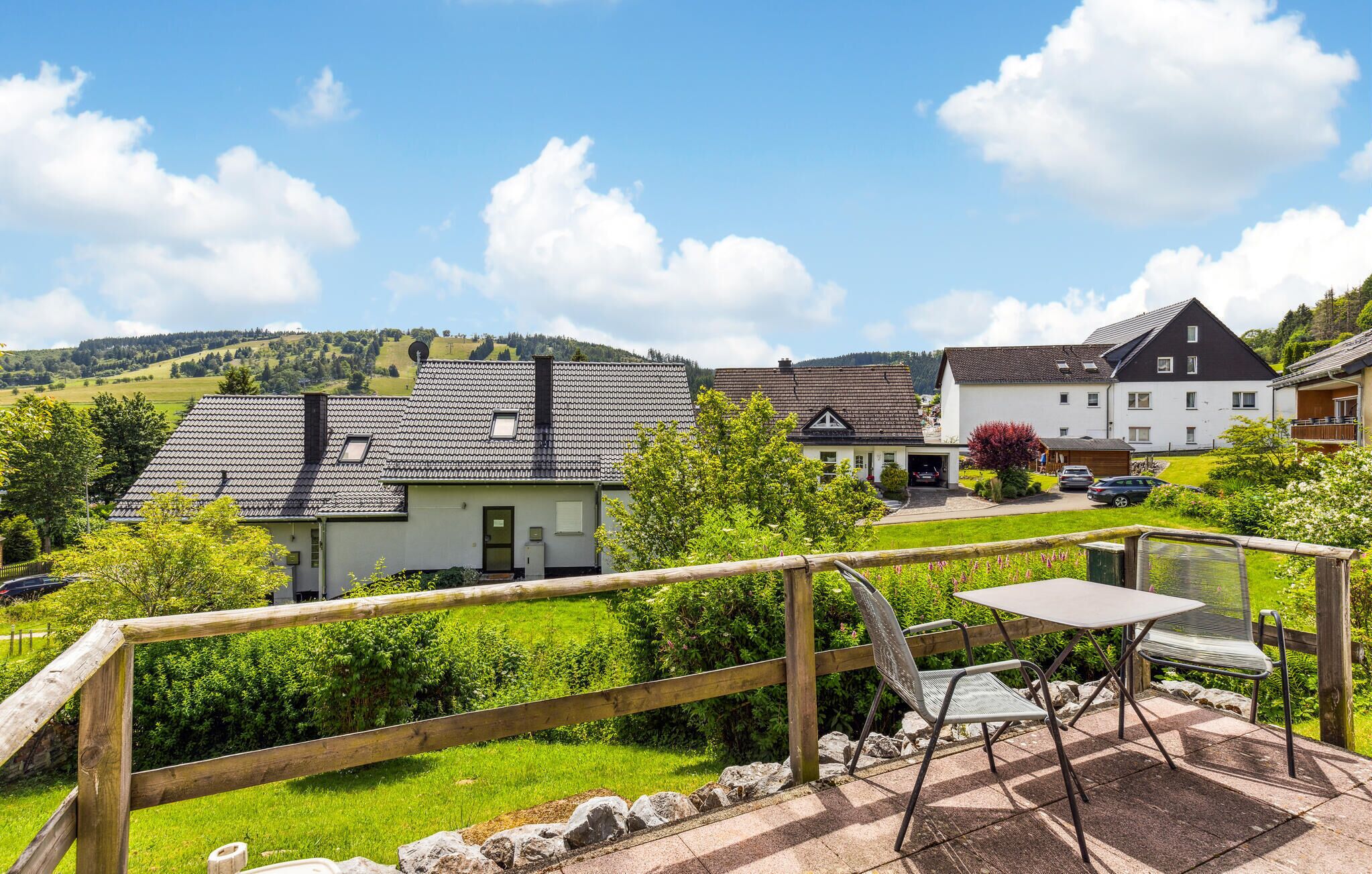 Un quartier résidentiel avec des maisons, une clôture en bois et une terrasse avec une table et des chaises.