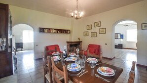 A dining area with a wooden table set for six, surrounded by red chairs. A brick fireplace is visible in the background, and there are framed pictures on the wall. - Nice home in Cetraro - San Pietro (Cetraro - San Pietro)