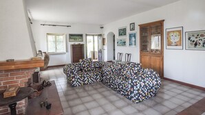 A living room with a checkered sofa set, a fireplace, and a dining area with a table and chairs. - Nice home in Cetraro - San Pietro (Cetraro - San Pietro)
