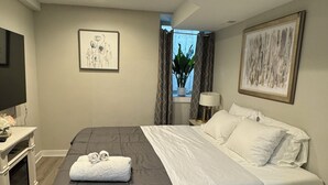 Une chambre moderne avec un grand lit, des tables de chevet, un téléviseur à écran plat et des œuvres d’art accrochées aux murs.
