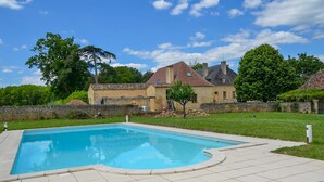 Una piscina con un muro de piedra y un edificio de piedra al fondo.