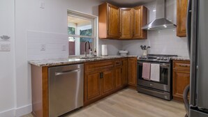 A modern kitchen with wooden cabinets, stainless steel appliances, and a tiled backsplash. - Sarasota modern house, heated saltwater pool, close to beaches and downtown! (Sarasota)