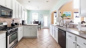 A modern kitchen with white cabinets, a central island, a microwave, stove, and dishwasher. - 5minutes direct to Kemah with the beaches and countless seafood restaurants  (Seabrook)
