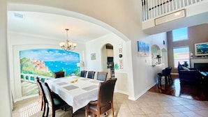 A dining area with a table set for six, a view of the sea through an archway, and a staircase leading to an upper level. - 5minutes direct to Kemah with the beaches and countless seafood restaurants  (Seabrook)