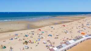 A beach with numerous sunbeds and umbrellas, a sandy shore, and a clear blue sky. - Cozy apartment in Oostende with WiFi (Oostende)