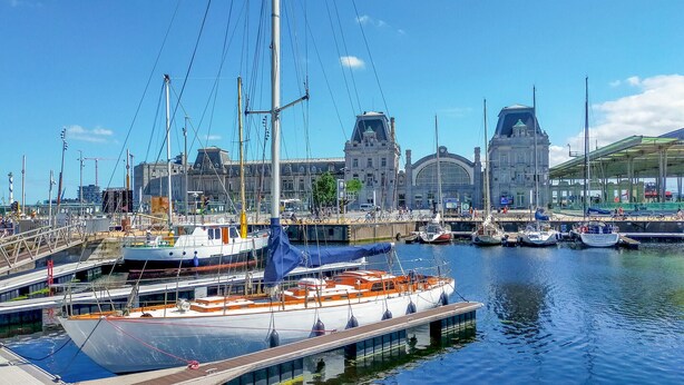 A marina with several boats docked, a bridge, and a historic building in the background. - Cozy apartment in Oostende with WiFi (Oostende)