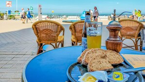 A table with a bottle of Blanche de Narmer, a glass of yellow drink, slices of bread, butter, and a pepper grinder on a blue table. - Cozy apartment in Oostende with WiFi (Oostende)