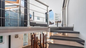 A modern interior with a staircase leading to an upper level, a glass door, and a view of the outside.