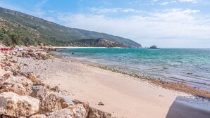 A beach with rocky terrain and a clear view of the sea.