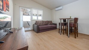 Una habitación pequeña y luminosa con una mesa de madera, un sofá y un televisor.