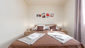Un dormitorio con una cama, dos mesitas de noche y una pared decorada con cuatro cuadros de flores.