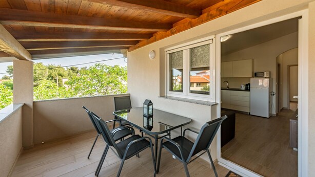 Un balcón con una mesa y sillas, vistas al exterior y un vistazo a la cocina.