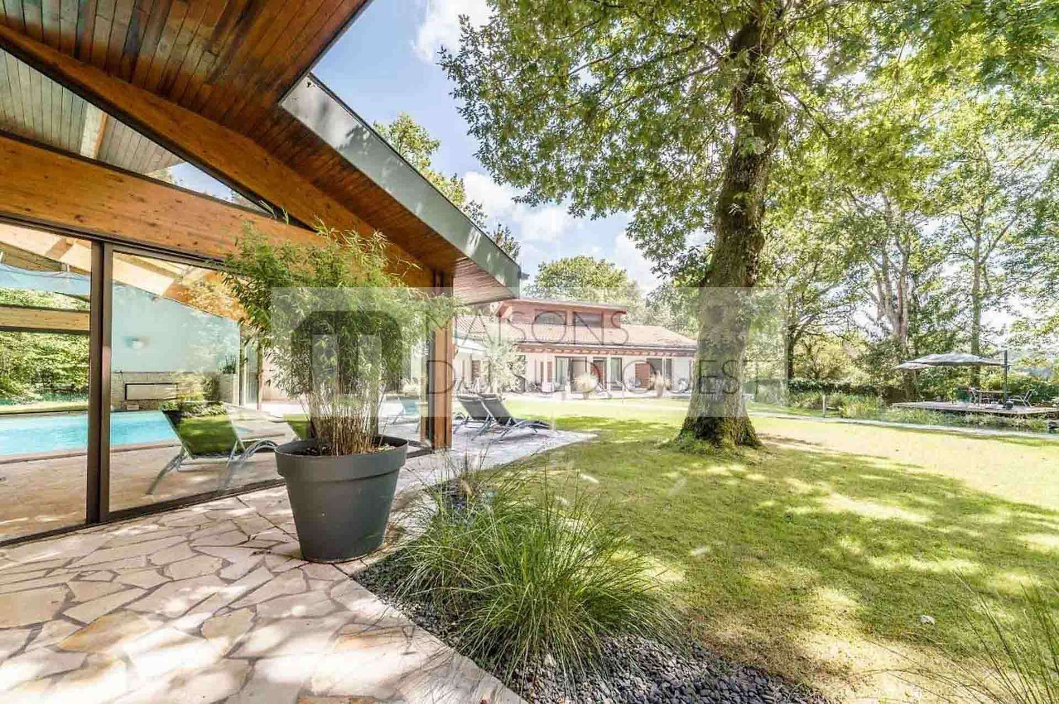 Uma casa moderna com piscina, janelas amplas e um gramado bem cuidado.