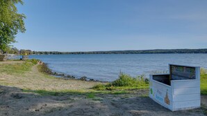 Une vue sur le lac, avec une structure de jeux en bois portant l’inscription « AND TOYS » et une zone de plage de sable.