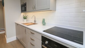 Una cocina moderna con armarios blancos, horno empotrado, lavabo y estufa.