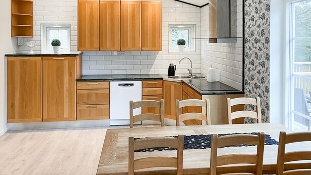Eine moderne Küche mit Holzausstattung, einem Geschirrspüler und einem Essbereich mit Tisch und Stühlen.