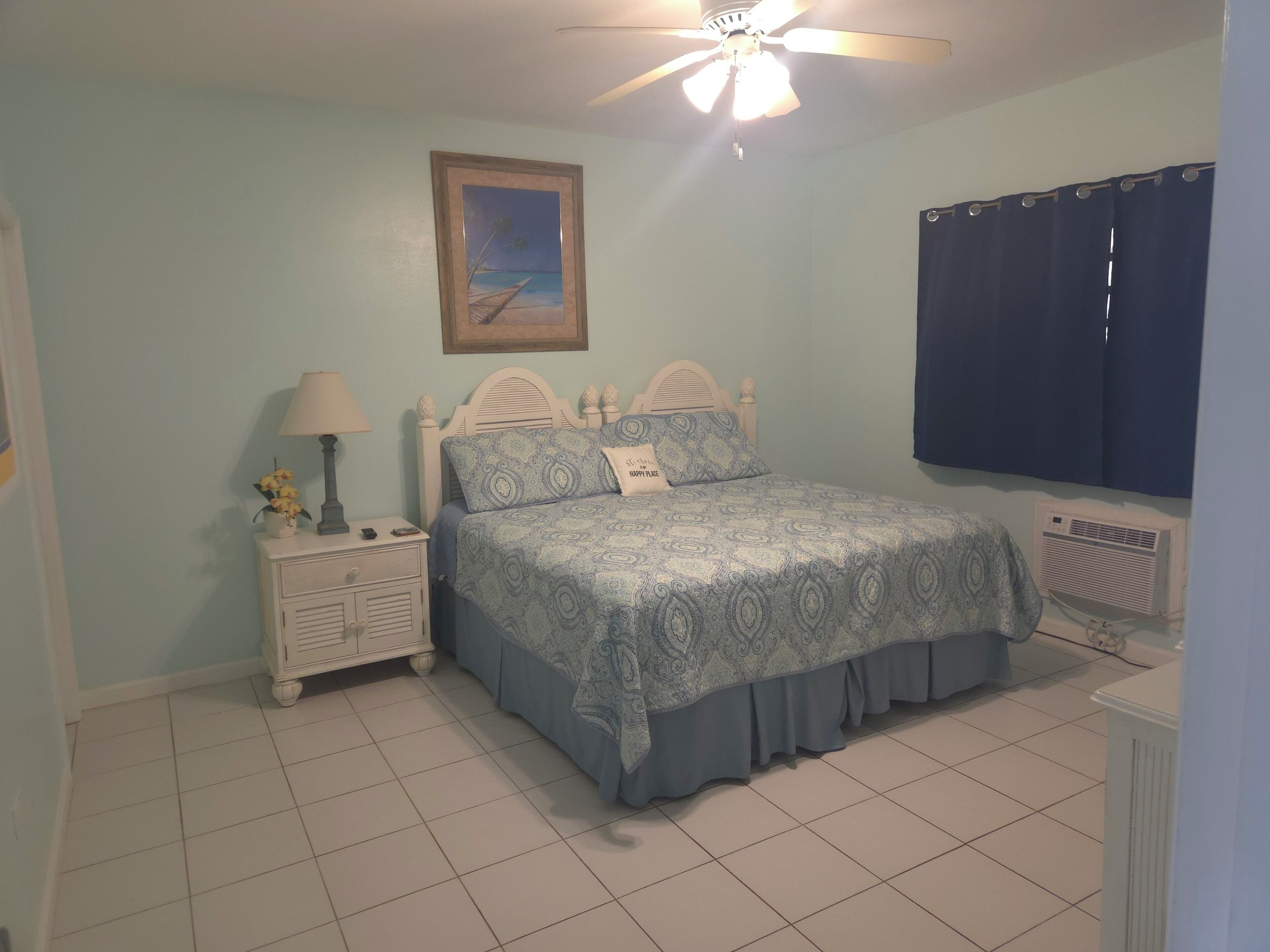 Une chambre à coucher avec un lit, une table de chevet, une lampe et un tableau au mur.