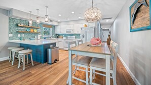 Una cocina moderna con una isla central, muebles blancos y una lámpara colgante.