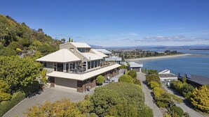 A modern hotel with multiple levels, large windows, and a view of the sea and hills.