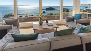 A modern living room with a large window overlooking a coastal view.
