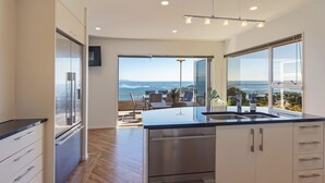 A modern kitchen with a view of the ocean, stainless steel appliances, and a large window.