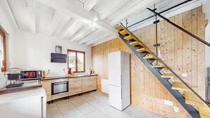 Une cuisine moderne équipée d’un four encastré, d’un réfrigérateur et d’un escalier en bois.