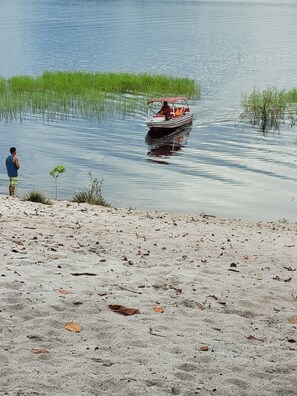 Un bateau sur une eau calme, avec une personne debout sur la rive.