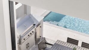An outdoor kitchen with a grill and a dining area with a table and chairs. - NEW Villa Mare LUX Sleeps 12 l Heated Pool l 2 Masters (Naples)