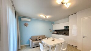Una cocina moderna con armarios blancos, una mesa de comedor con sillas y una pared azul claro.