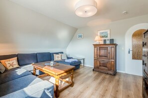 Ein gemütliches Wohnzimmer mit einem blauen Sofa, einem Holztisch und einem Schrank.