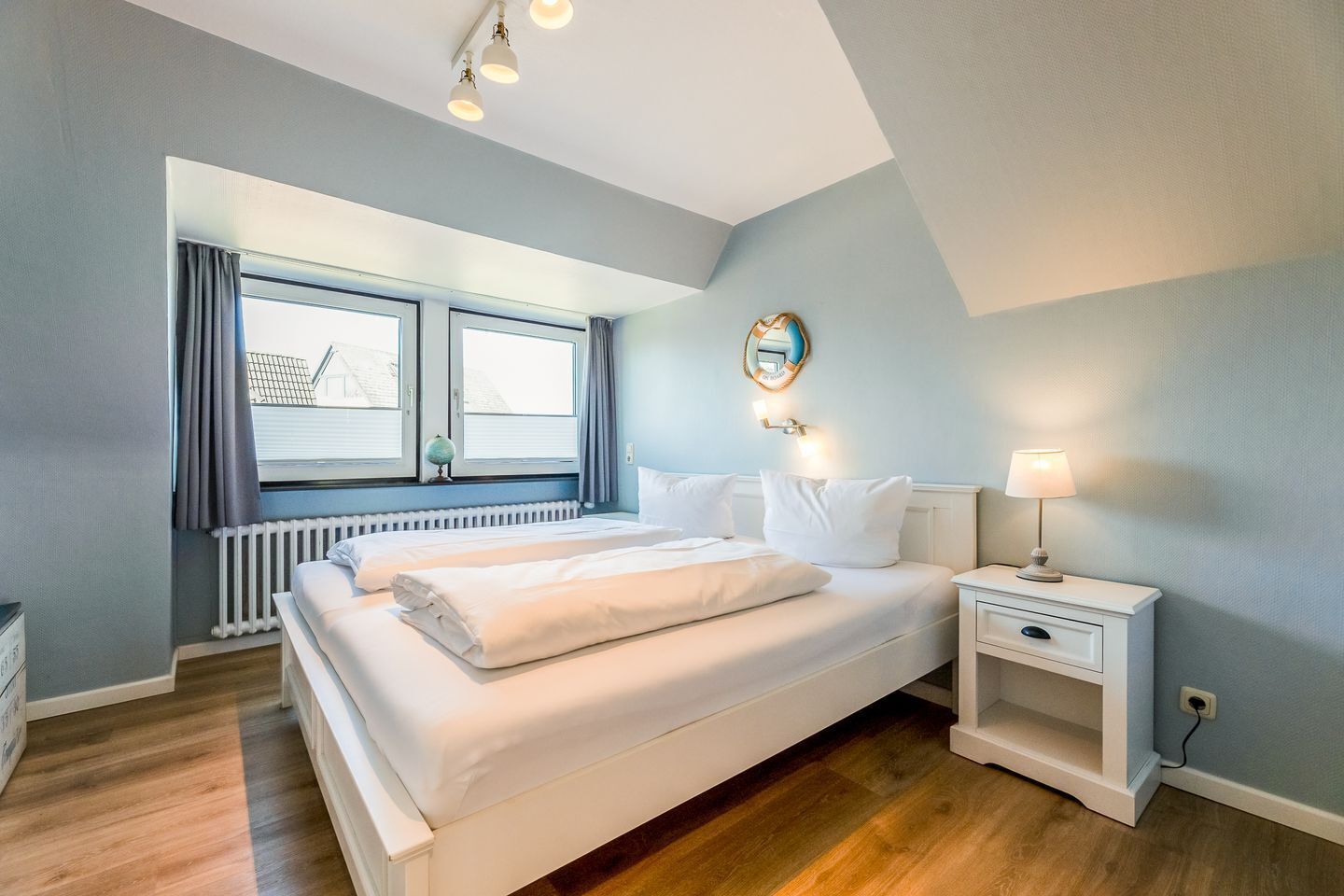A bedroom with a large bed, a nightstand, a globe, and a window with curtains.