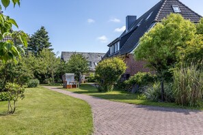 Ein Wohnhaus mit gepflasterter Auffahrt, Ziegelhaus und gepflegtem Garten.