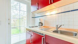 Een moderne keuken met rode kastjes, een wit aanrecht, een roestvrijstalen spoelbak en een koffiezetapparaat.