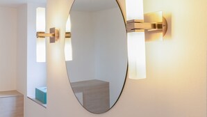 Een spiegel met een ronde vorm en een wandlamp.