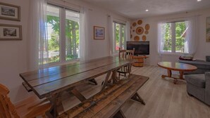 Un amplio salón con una gran mesa de comedor de madera, un televisor y un sofá.