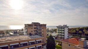 A coastal hotel with multiple floors, balconies, and a view of the sea.