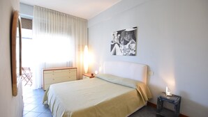 A bedroom with a bed, bedside table, lamp, and a painting on the wall.