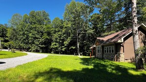 A house with a stone foundation and a brown roof, surrounded by a well-maintained lawn and trees. - Merlot- 2 bedroom Cottages near Jones von Drehle (Thurmond)