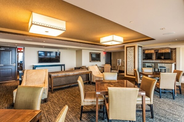 A hotel lobby with a billiards table, seating area, and a bar/lounge with televisions.