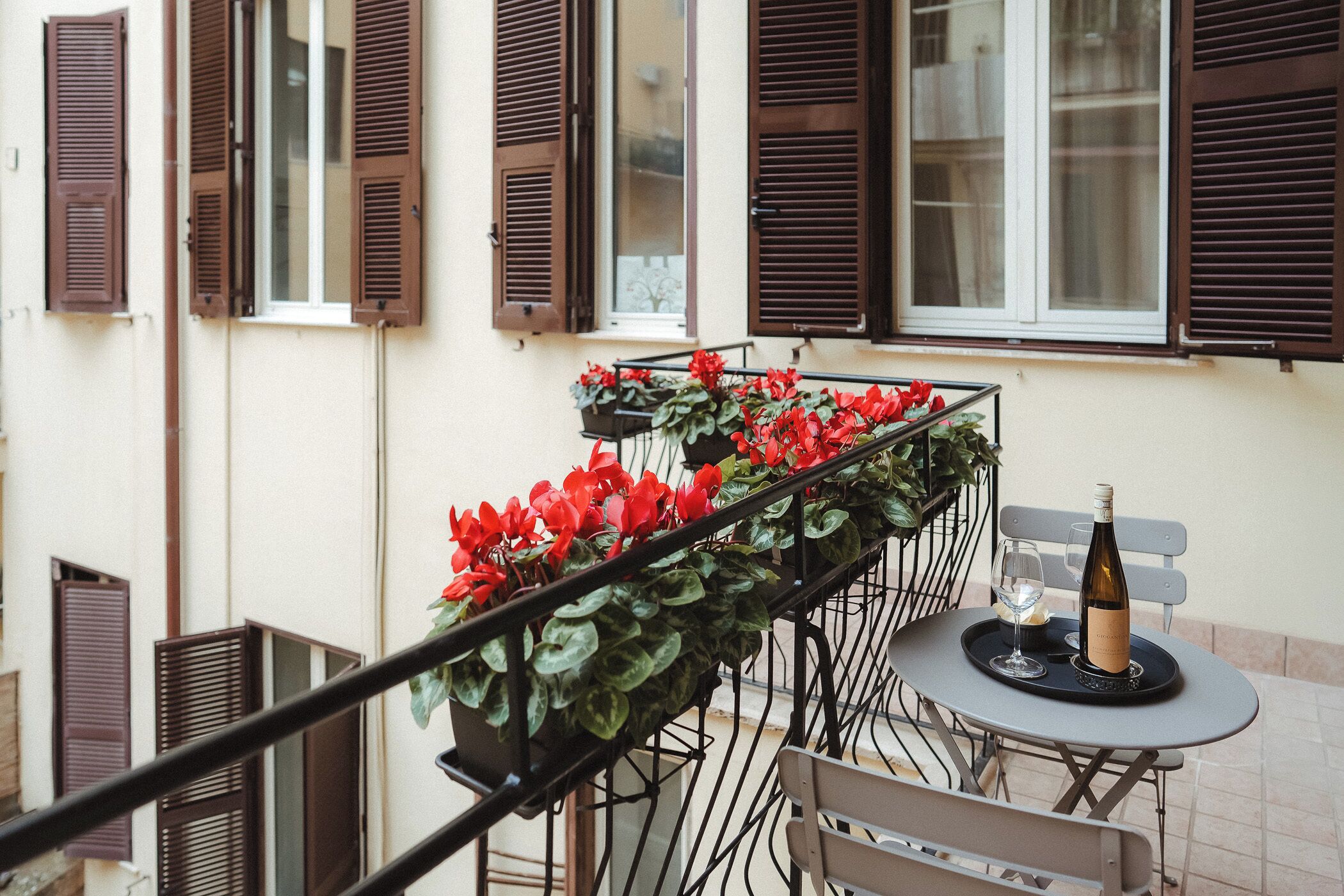 Ein Balkon mit einem Tisch für zwei Personen, ausgestattet mit einer Weinflasche und Gläsern.