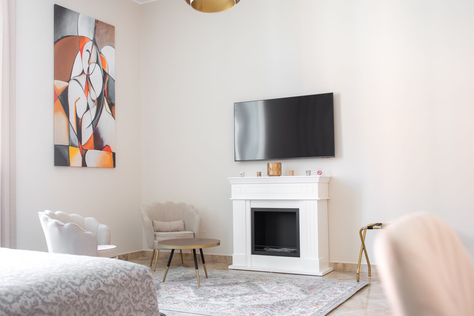 Una sala de estar moderna con chimenea, un televisor de pantalla plana, un sillón blanco y arte abstracto en la pared.