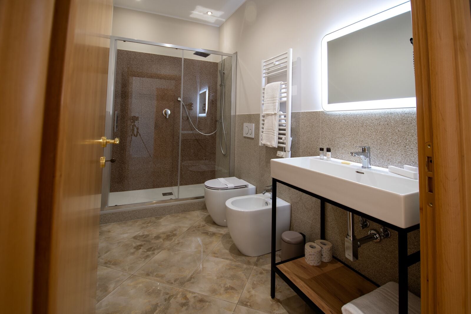 Un bagno moderno con doccia vetro, lavandino bianco e water.