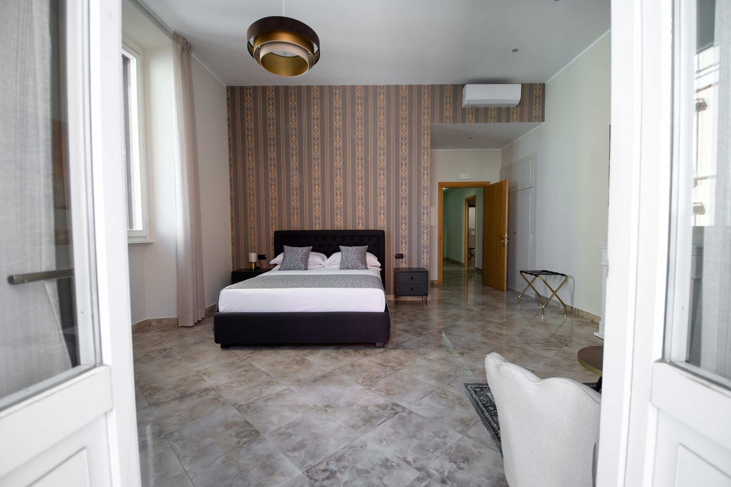 A hotel room with a large bed, a bedside table, a chair, and a small table.