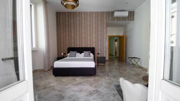 A hotel room with a large bed, a bedside table, a chair, and a small table.