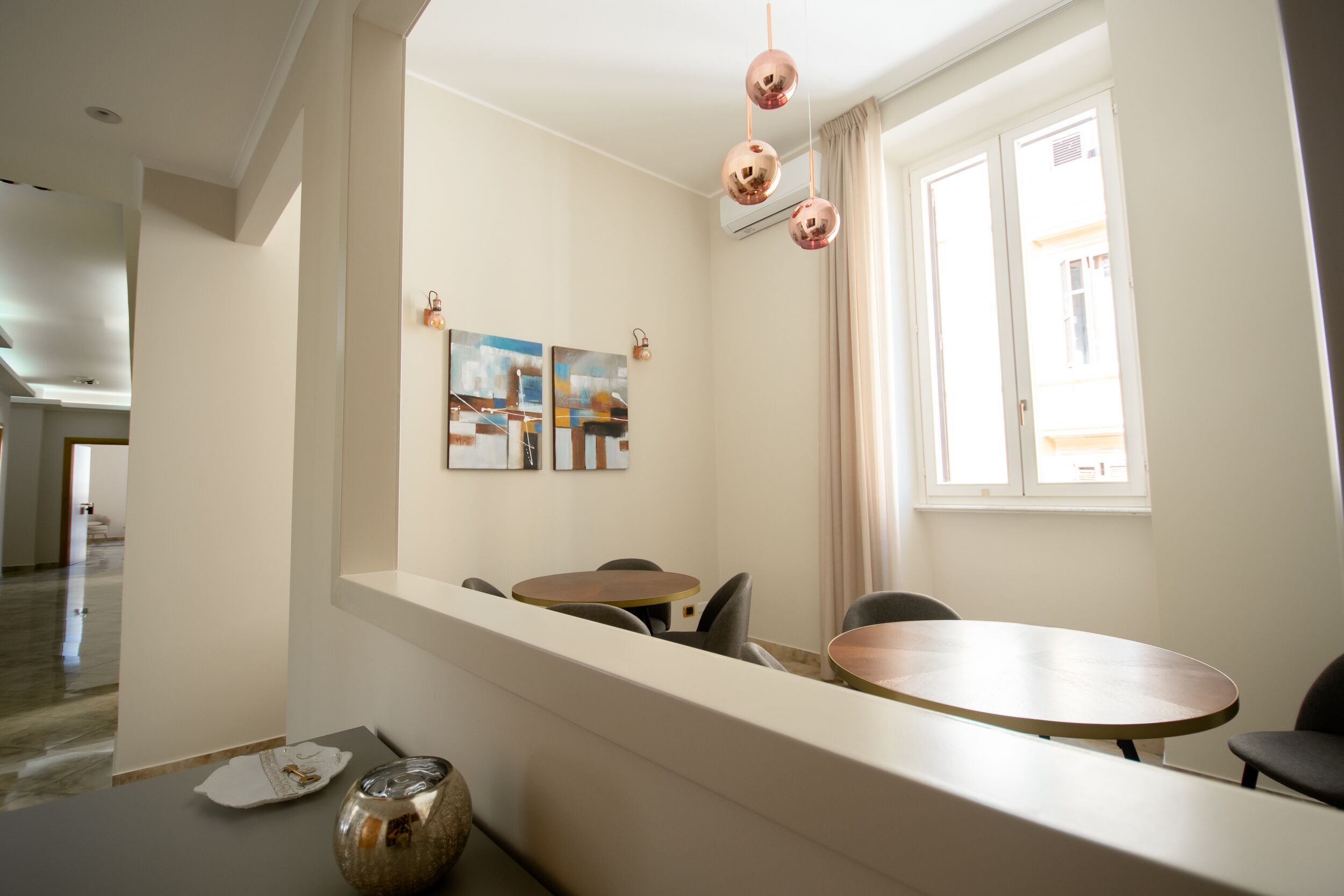 Ein moderner Essbereich mit einem runden Tisch und Stühlen, einer dekorativen Vase und Kunstwerken an der Wand.
