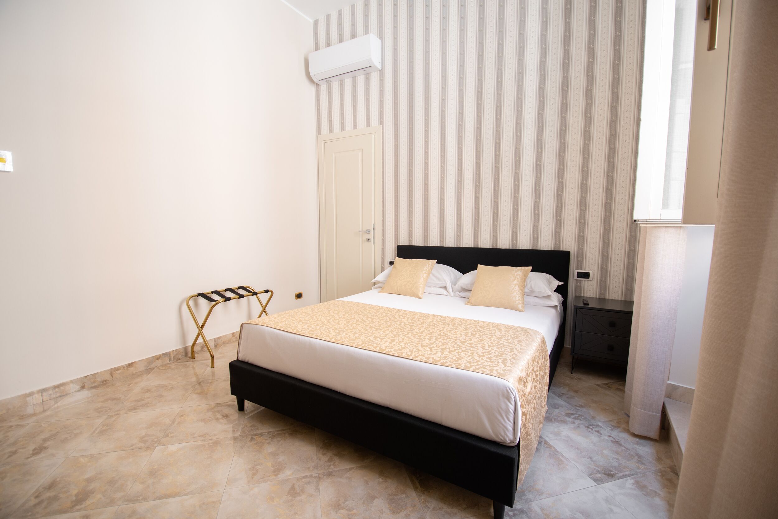 Une chambre à coucher bien rangée, avec un lit, des tables de chevet et une fenêtre.